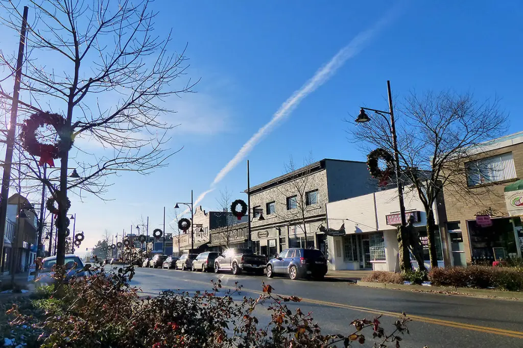 Historic Cloverdale Town Centre on 176 Street — heritage brick storefronts with festive wreaths on the lamp standards, the village high street that anchors the Cloverdale Rodeo weekend