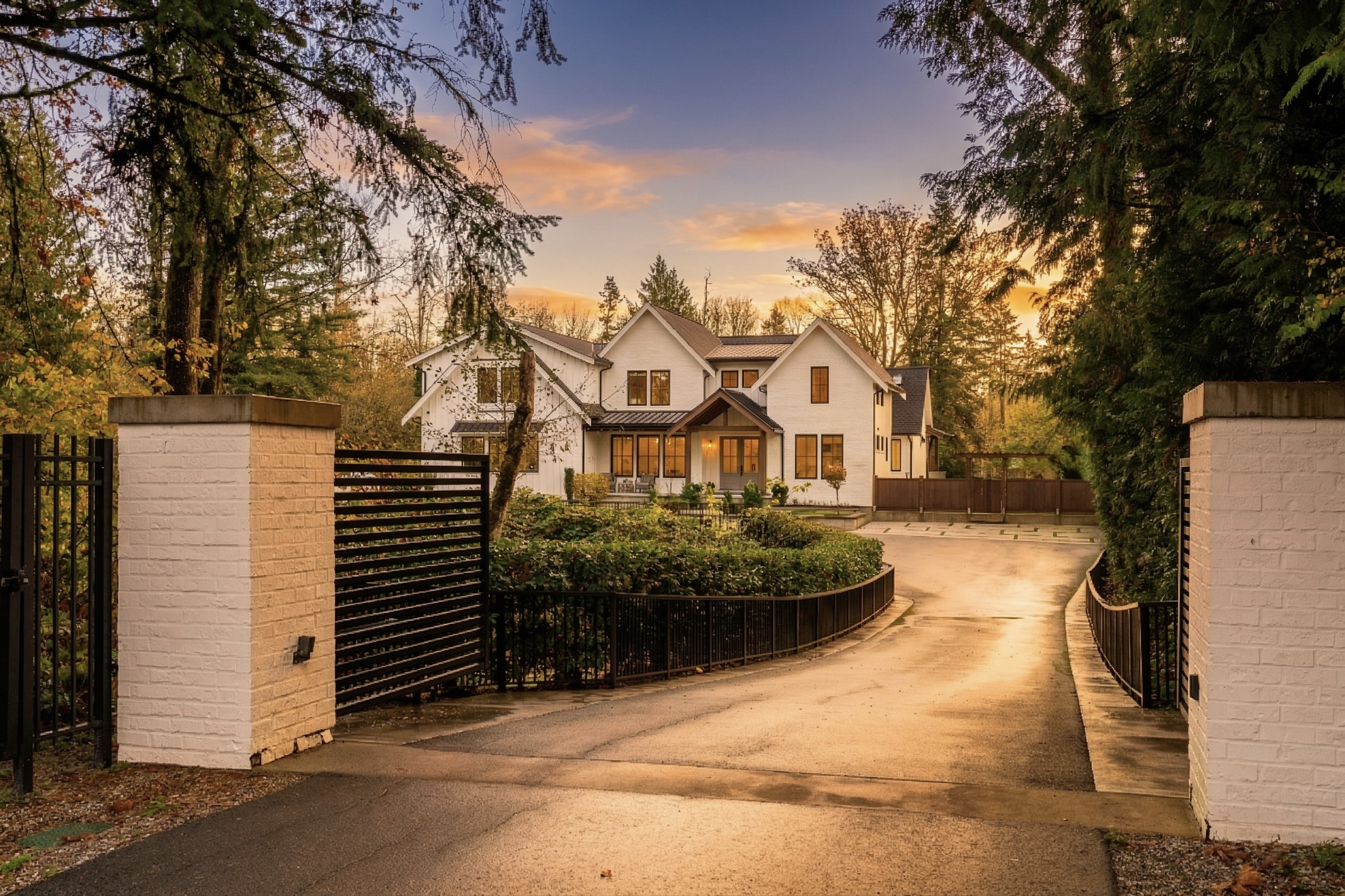 10128 McKinnon Crescent in Fort Langley: a modern farmhouse behind white brick gate posts, at golden hour