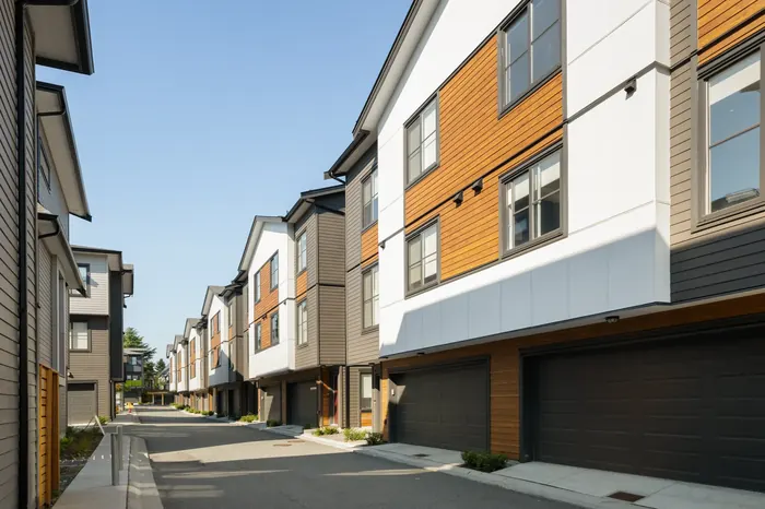 Photograph looking along an internal lane at Elwynn Green, with garage doors on the ground floor and wood and white siding above