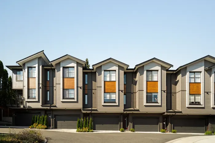 Photograph of a row of Elwynn Green townhomes with four gabled fronts, orange accent panels and garages at ground level