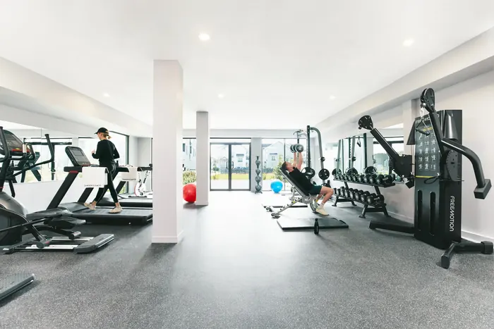 Photograph of a fitness room with treadmills and weight machines and people exercising