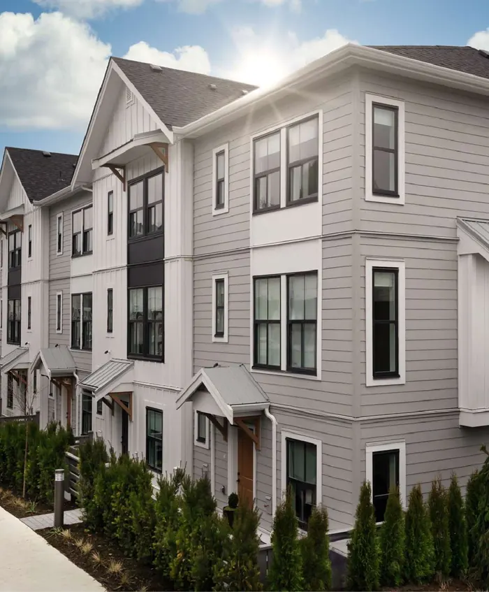Image of Heath West townhomes with white and grey siding and dark window frames, seen along the planting at the front