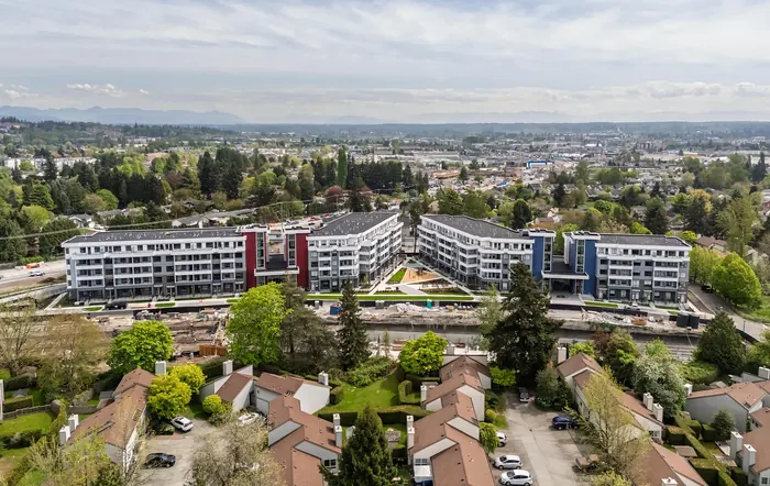 Aerial photograph of Park & Maven’s condo buildings among trees and surrounding neighbourhoods, with the Fraser Valley beyond