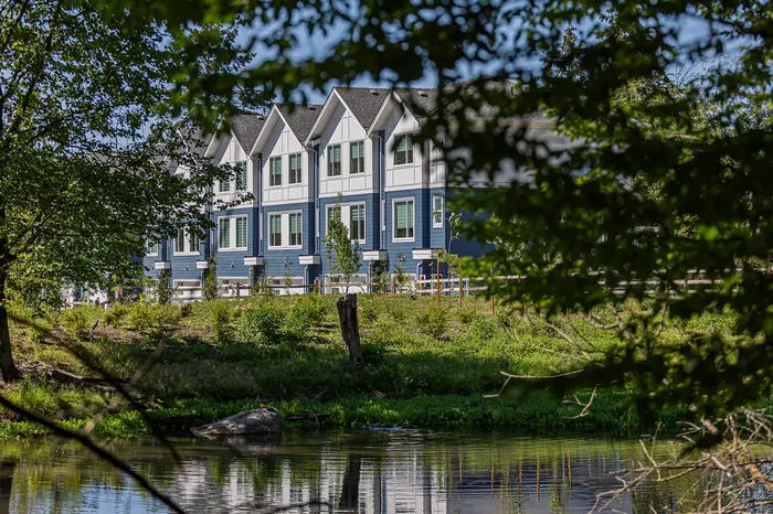Photograph of Park & Maven townhomes seen across a pond through trees