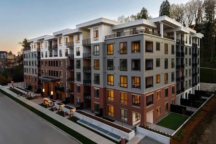 Drone photograph of The Mason, a six-storey condo building with red brick at the lower floors and white and grey above, at dusk