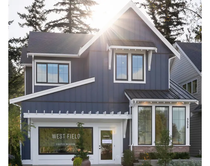A navy two-storey house with white trim at 3038 Brigette Street, with a West Field sign in its front window