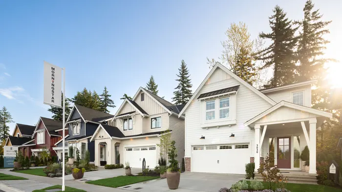 A row of new farmhouse-style detached houses with double garages along a street at West Field